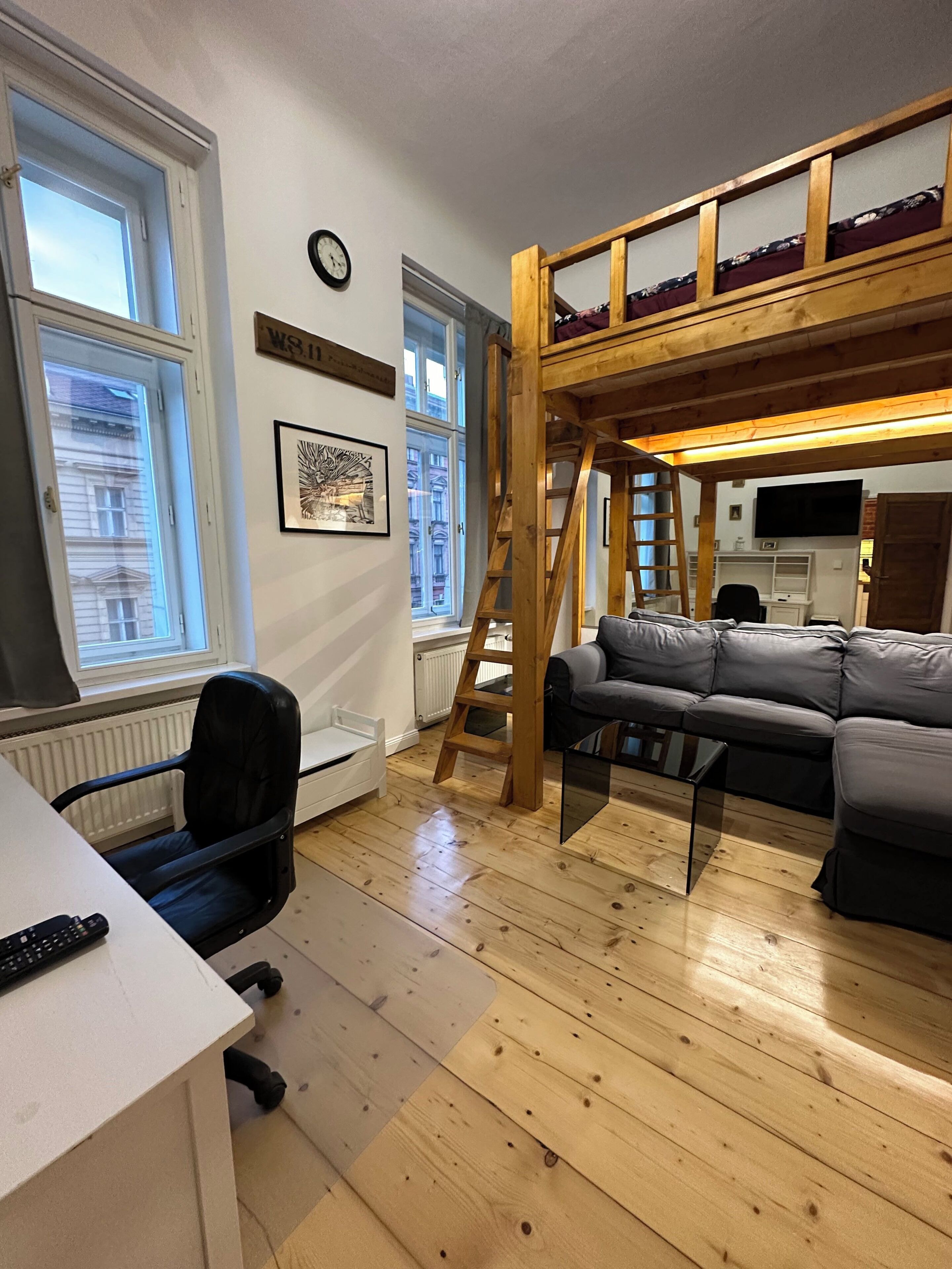 A room with a bunk bed, a desk, a chair, and a sofa.