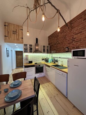 Une cuisine moderne avec des meubles en bois, un mur en briques et un coin repas comprenant une table et des chaises.