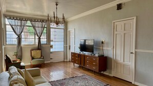 Una sala de estar con un sofá, televisor, mueble de madera y una alfombra estampada.