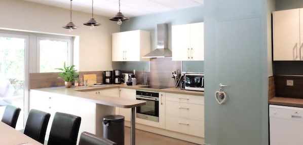 A modern kitchen with a central island, built-in appliances, and a dining area with chairs.