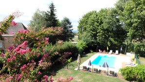A backyard with a swimming pool, surrounded by lush greenery and flowering plants. - Air-conditioned Gîte "La Maison du Parc" with Private Pool near Nuits-Saint-Georges (Argilly)