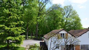 A residential area with a white house, a driveway, and a large tree. - Air-conditioned Gîte "La Maison du Parc" with Private Pool near Nuits-Saint-Georges (Argilly)