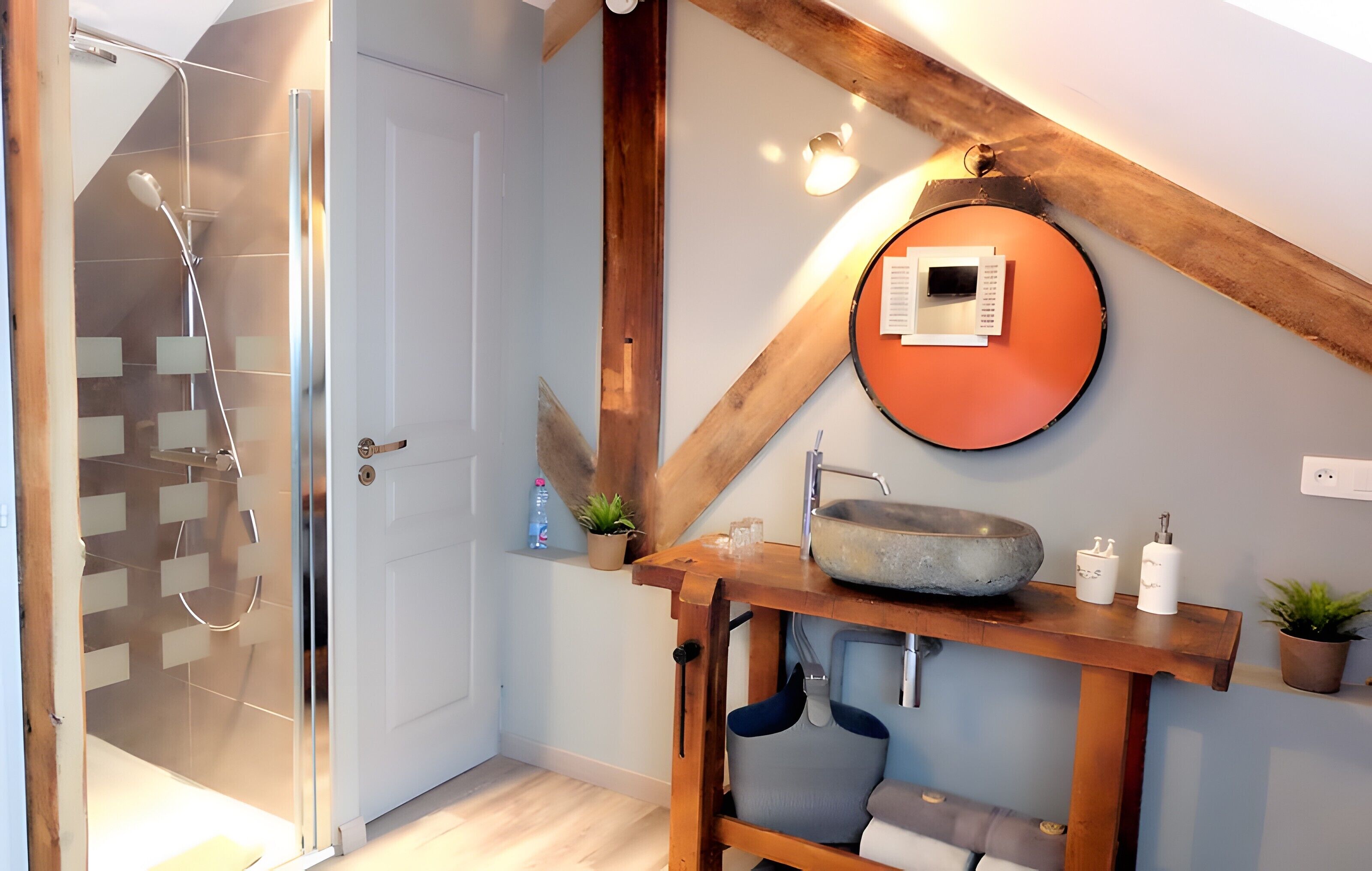 Une salle de bain moderne avec une douche à parois de verre, un meuble-lavabo en bois et un miroir rond.