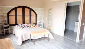 A bedroom with a bed, a bench, a desk, and a wardrobe.