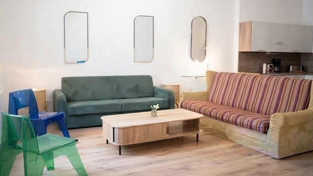 Ein Wohnzimmer mit einem grünen Sofa, einem gestreiften Sofa, einem Couchtisch und zwei Sesseln.