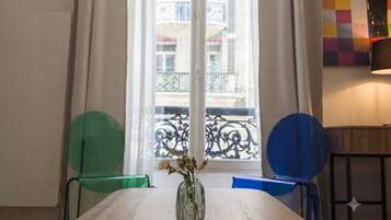 Una habitación con una mesa de madera, un jarrón con flores y vistas a un balcón con barandilla.