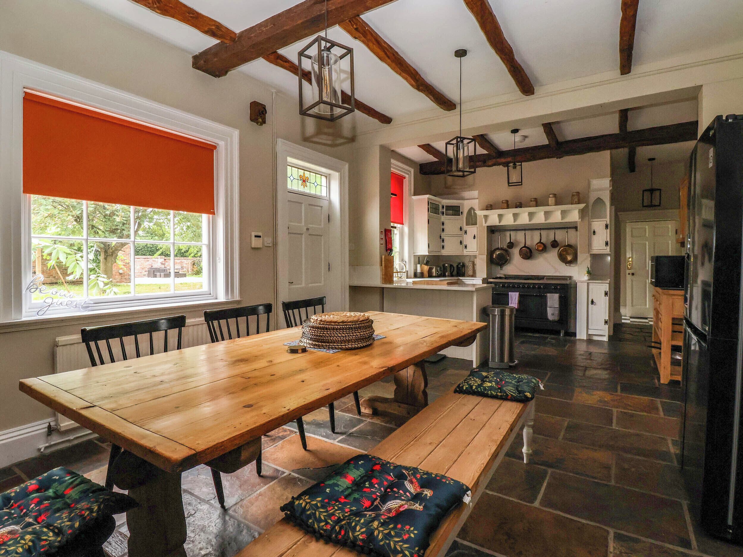 A spacious kitchen with a large island, wooden benches, and a dining table.