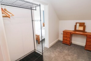 Ein Schlafzimmer mit begehbarem Kleiderschrank, einem Holzschrank und einem Spiegel.