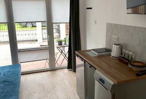 A compact kitchen with a dishwasher, a coffee maker, and a small dining table. - Apartment for 2 People Near the sea (Mielno)