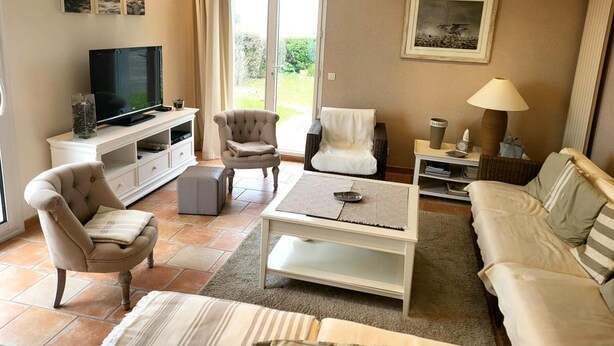 A living room with a television, seating, a coffee table, and a painting on the wall. - Villa 'Front De Mer Les Cordylines' with Sea View, Private Terrace and Wi-Fi (Saint-Germain-sur-Ay)