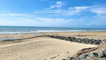 Une plage bordée d’un rivage rocheux, un ciel dégagé et une mer calme.