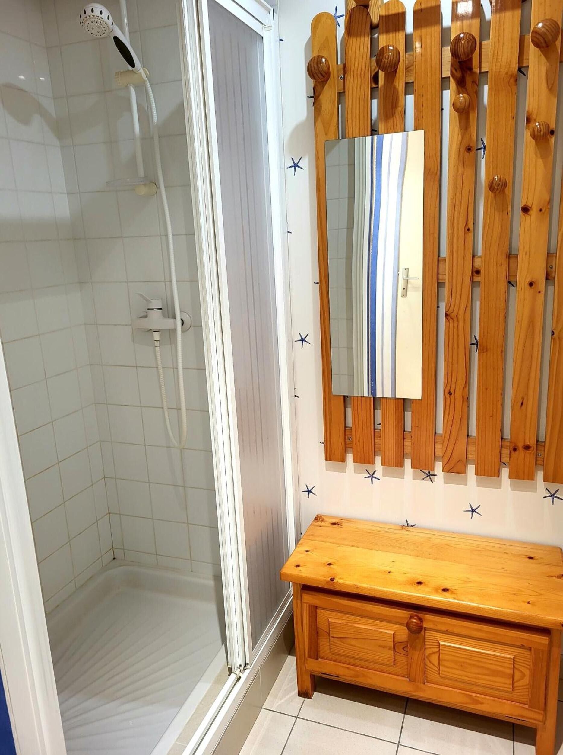 Un baño con ducha, tocador de madera y espejo.