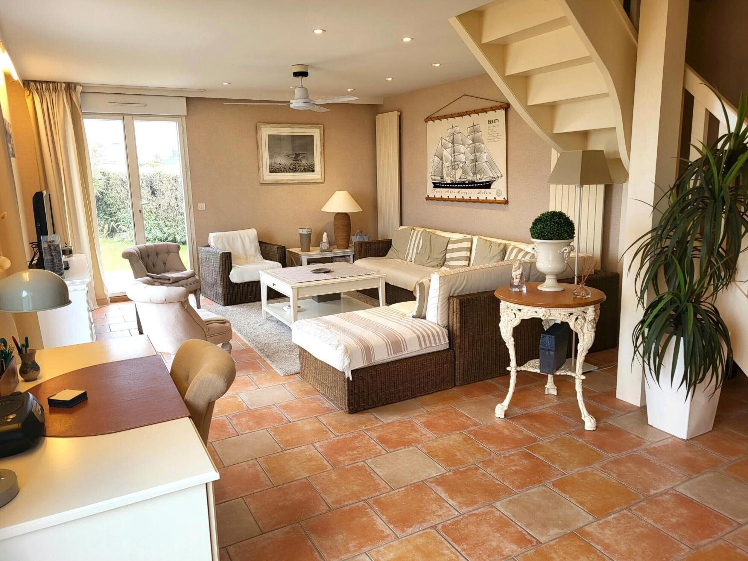 A spacious living area with a sofa set, a dining table, and a staircase.