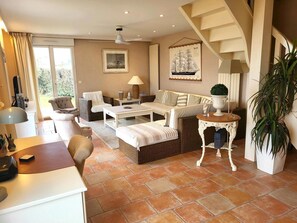 A spacious living area with a sofa set, a dining table, and a staircase. - Villa 'Front De Mer Les Cordylines' with Sea View, Private Terrace and Wi-Fi (Saint-Germain-sur-Ay)