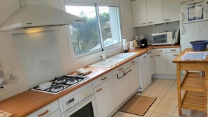 A modern kitchen with white cabinetry, a wooden countertop, a gas stove, an oven, a microwave, and a sink. - Villa 'Front De Mer Les Cordylines' with Sea View, Private Terrace and Wi-Fi (Saint-Germain-sur-Ay)