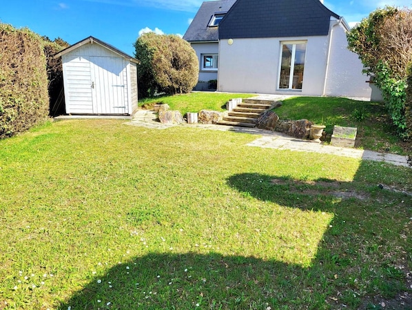 A residential property with a well-maintained lawn, a detached garage, and a house with a sloped roof.