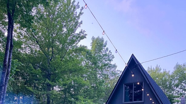 A house with a deck, outdoor seating, and a fire pit. - Cozy, Private Dog-Friendly A-Frame Cabin: Mins to Hiking + Adorable Towns (Weathersfield)