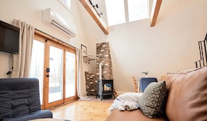 Una sala de estar con sofá, televisión, chimenea y un ventanal grande.