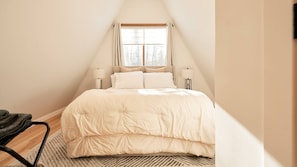 Un dormitorio con cama, ventana y dos lámparas de noche.