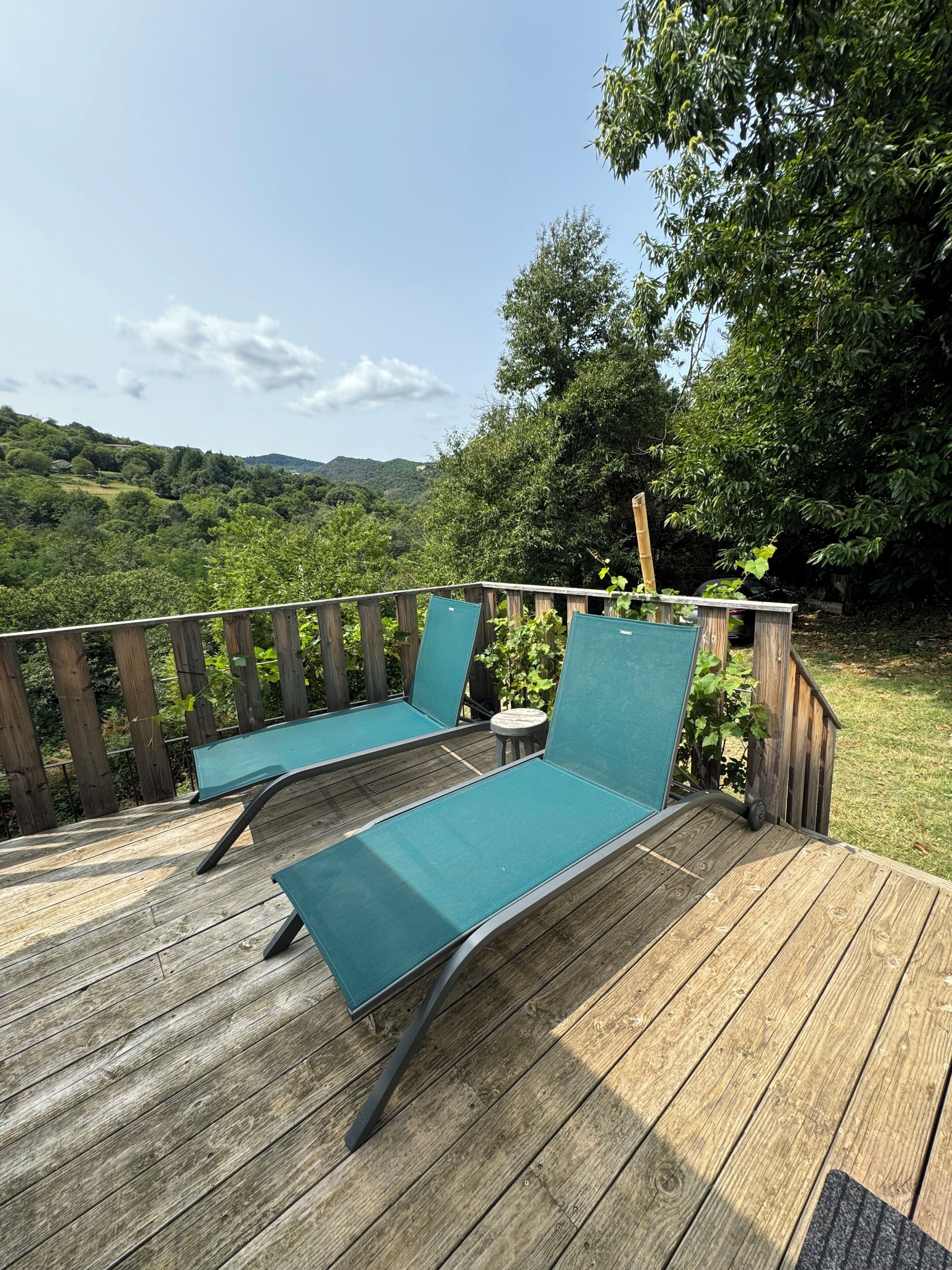 A wooden deck with two lounge chairs and a small table.