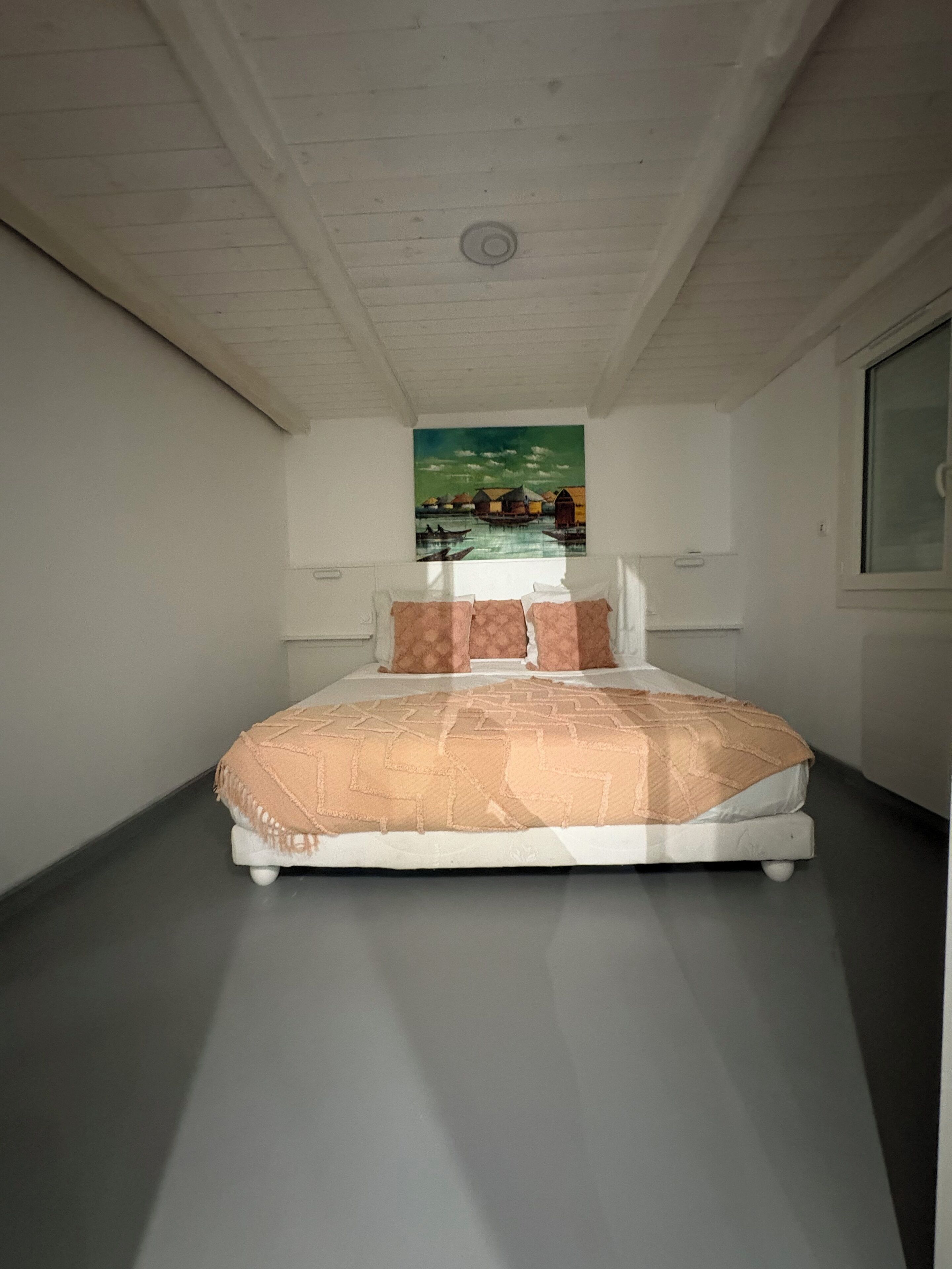 Une chambre à coucher avec un lit, un tableau au mur et une fenêtre.