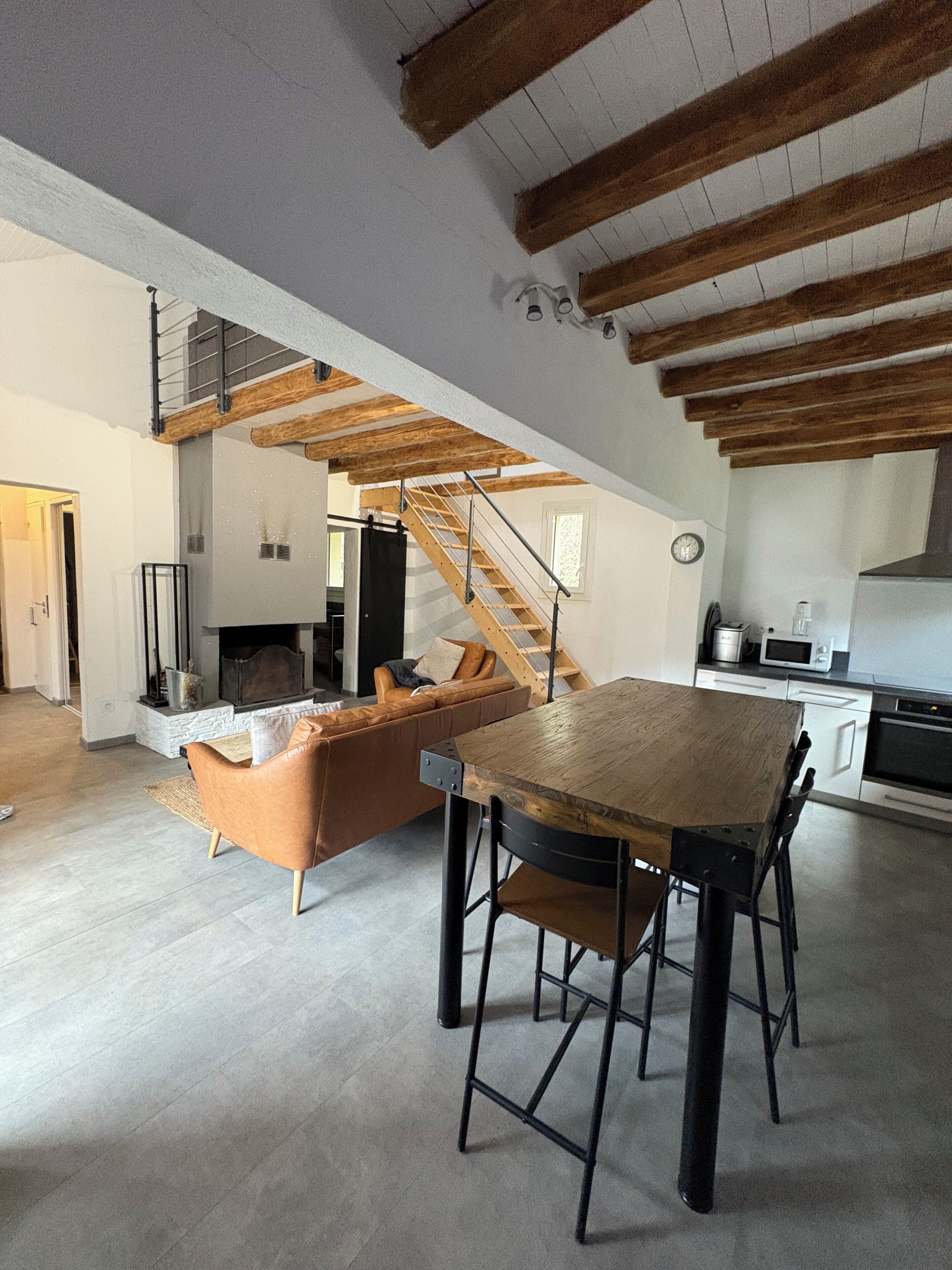 Ein moderner Wohnraum mit einem Holzesstisch, einer Couch und einer Treppe zu einer oberen Ebene.