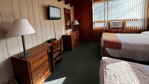 A room with two beds, a desk with a lamp, a dresser, and a television on the wall. - Cozy 1BR hotel room, Hamilton - #349 Iroquois (Hamilton)