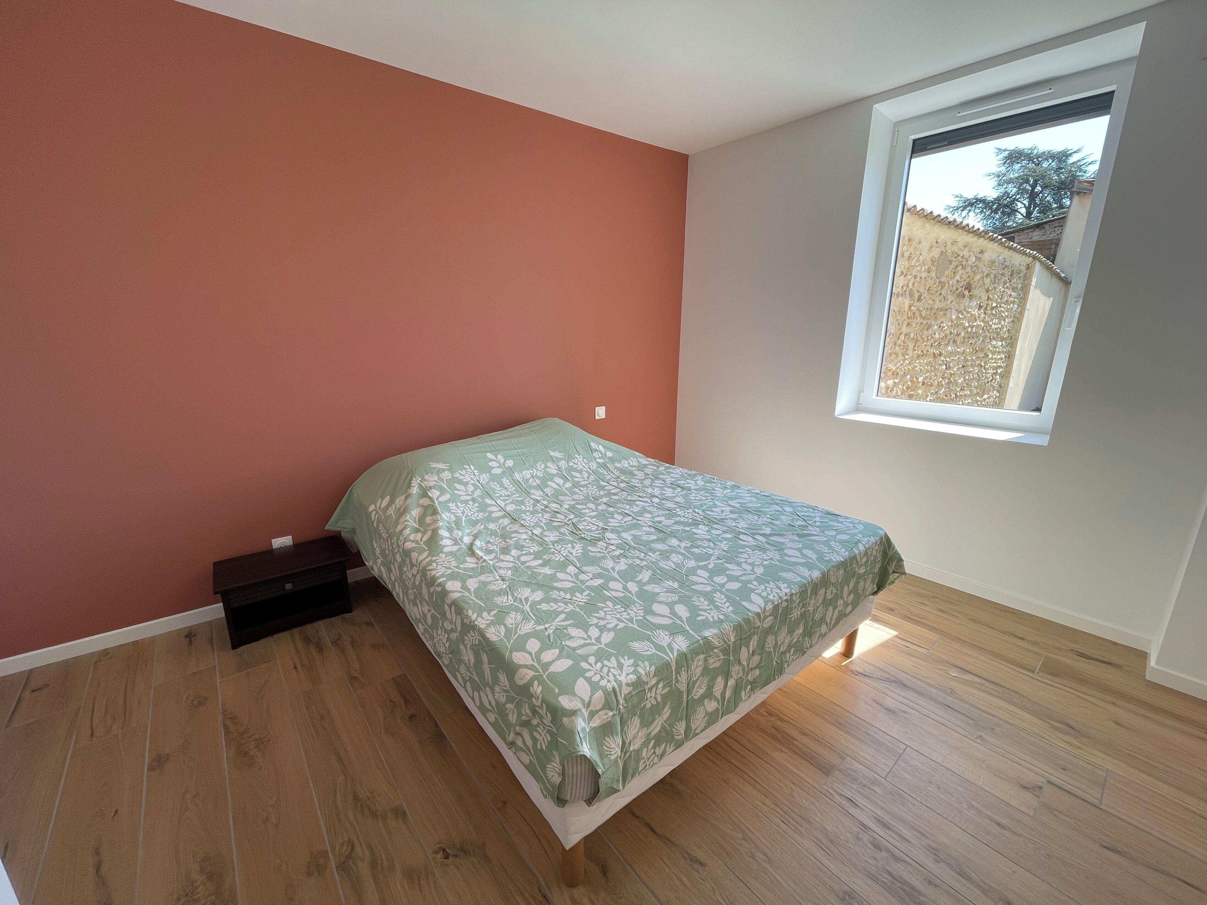 Ein Schlafzimmer mit einem Bett, einem Fenster und Holzboden.
