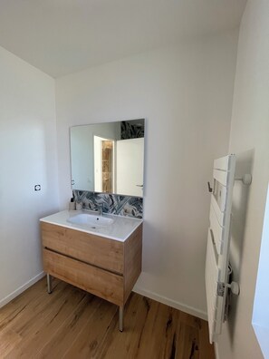 A bathroom with a wooden vanity, a white sink, and a large mirror.