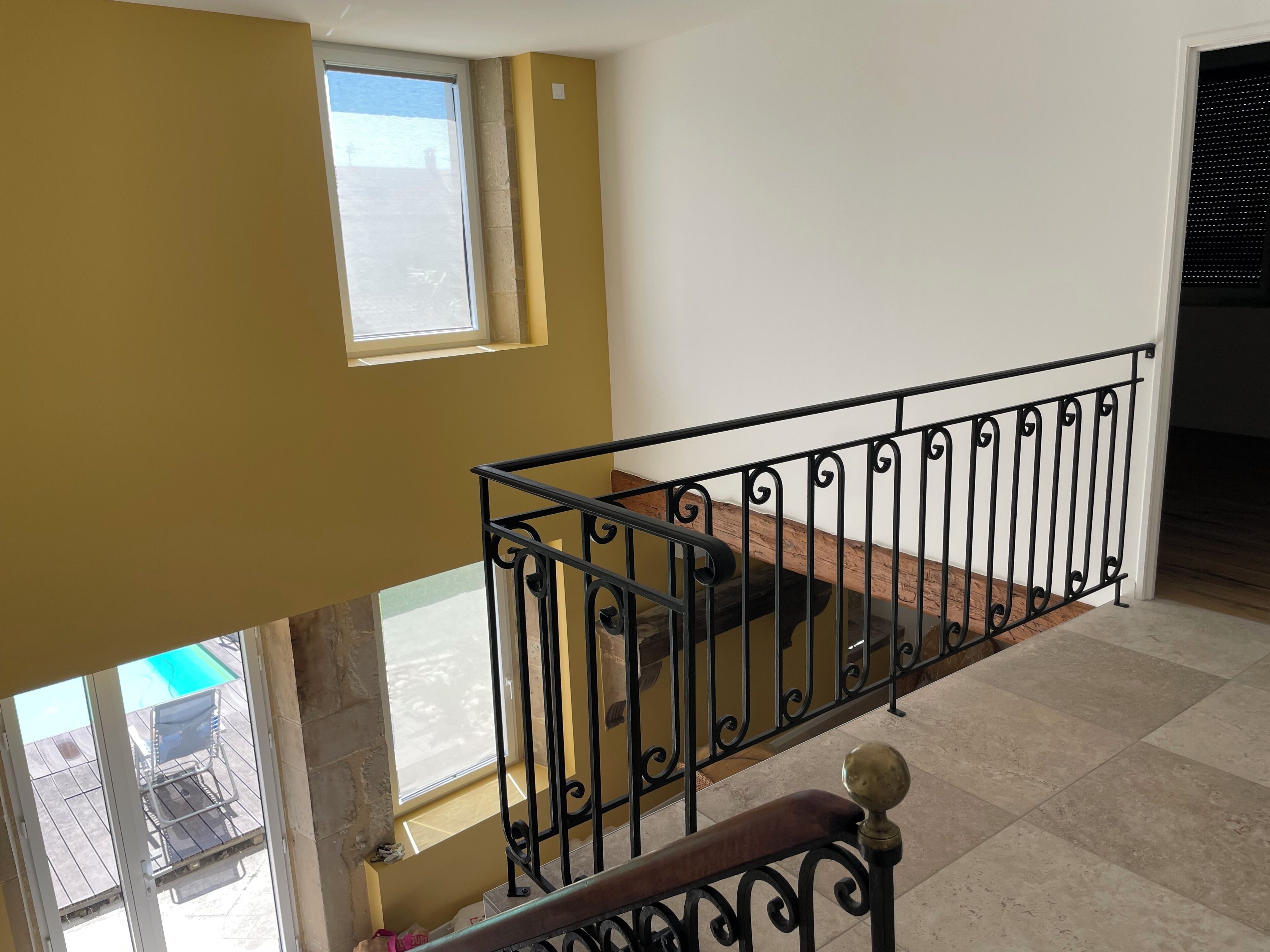 A balcony with a metal railing, a window, and a view of a swimming pool.