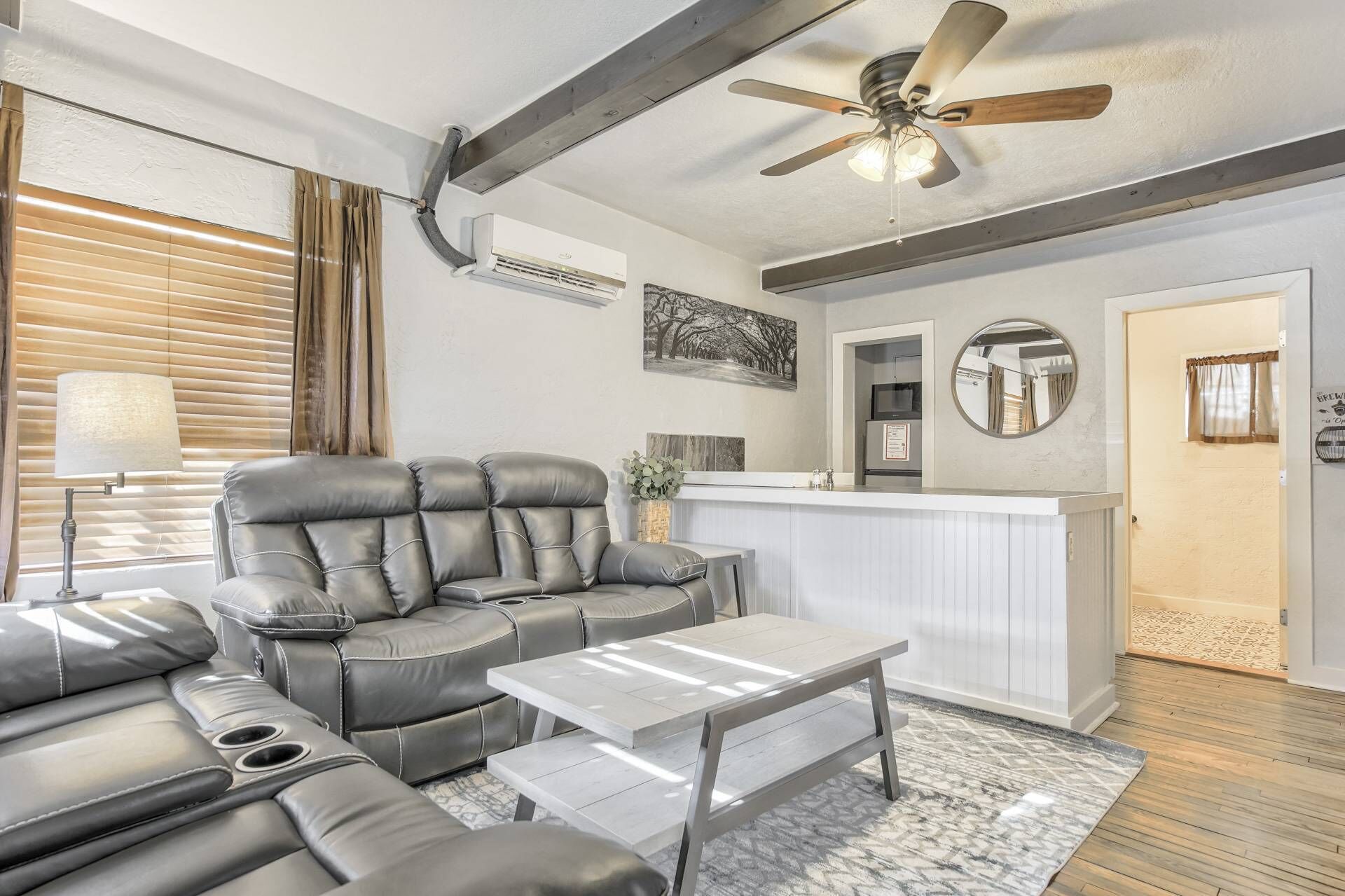 A modern living room with a leather sofa, a coffee table, and a ceiling fan.