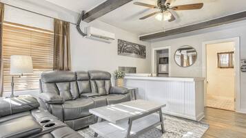 A modern living room with a leather sofa, a coffee table, and a ceiling fan.