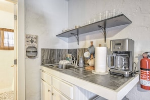 A kitchen with a stainless steel sink, a coffee maker, and a fire extinguisher.