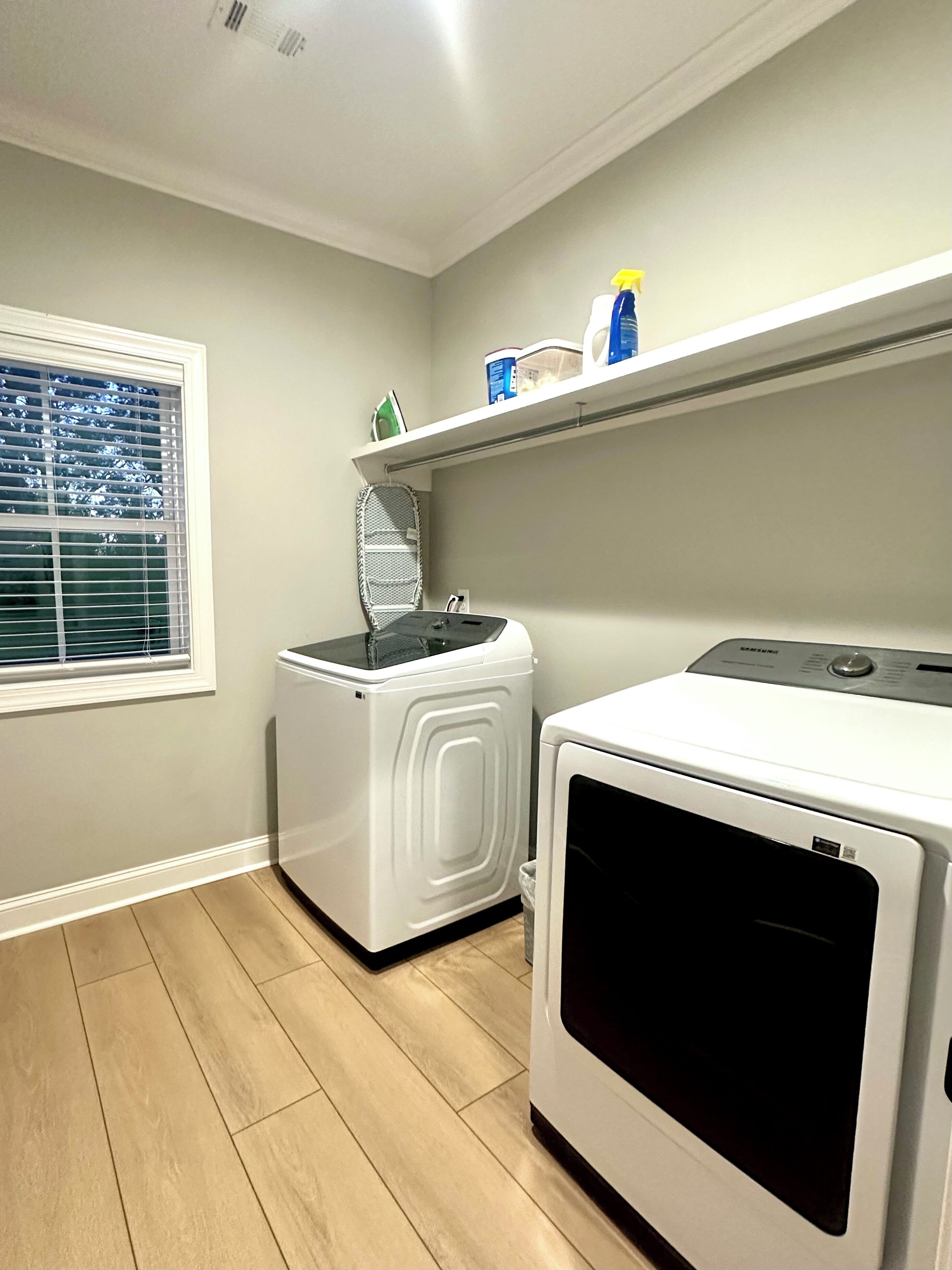 A laundry room with a washing machine, dryer, and ironing board.