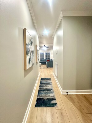 A hallway with a wooden floor, a black and white rug, and a ceiling fan.