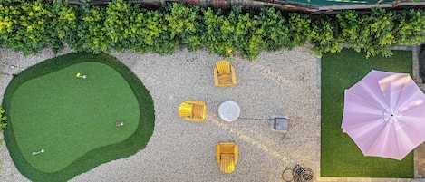 An aerial view of a rooftop garden with a lawn, seating area, and a large umbrella.