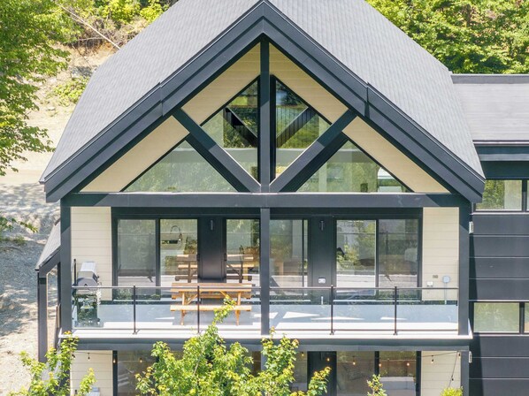 A modern two-story house with a large glass balcony and a dining area.