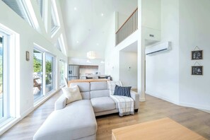 A modern living room with a sectional sofa, a dining table, and a kitchen in the background. - Nature & Mountain | Altisud (Saint-Philémon)