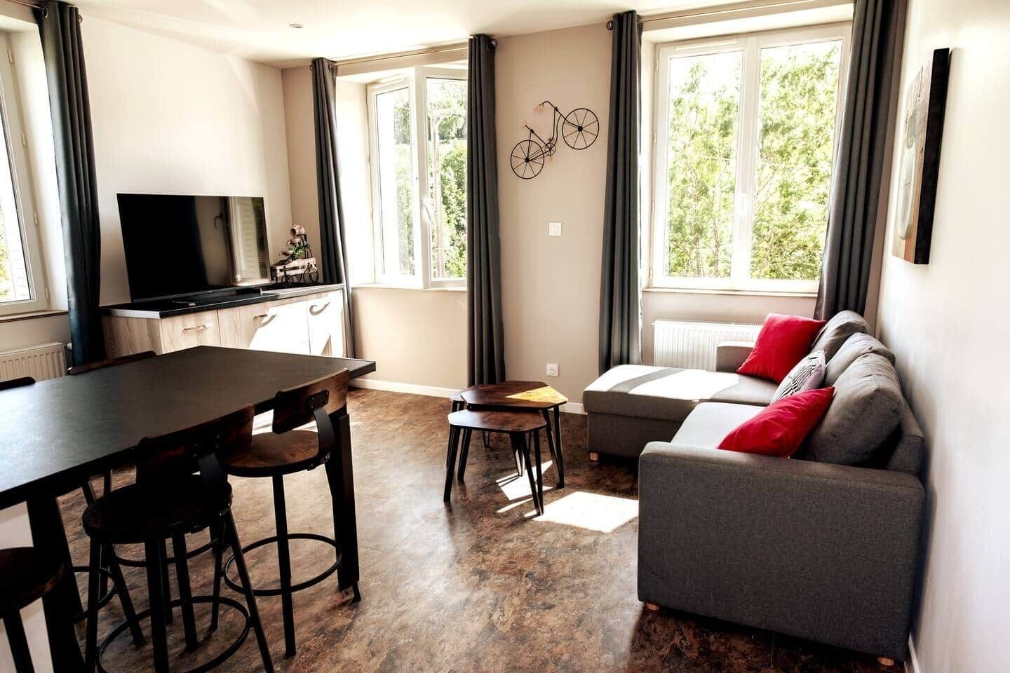 A modern living room with a sofa, a dining table, and a TV.
