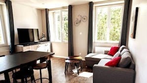A modern living room with a sofa, a dining table, and a TV.