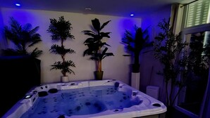 A hot tub with steps leading up to it, surrounded by potted plants and a window.