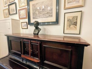 A room with a long wooden desk, framed artworks on the wall, and a bust sculpture. - Raphael Rooms (Peterborough)