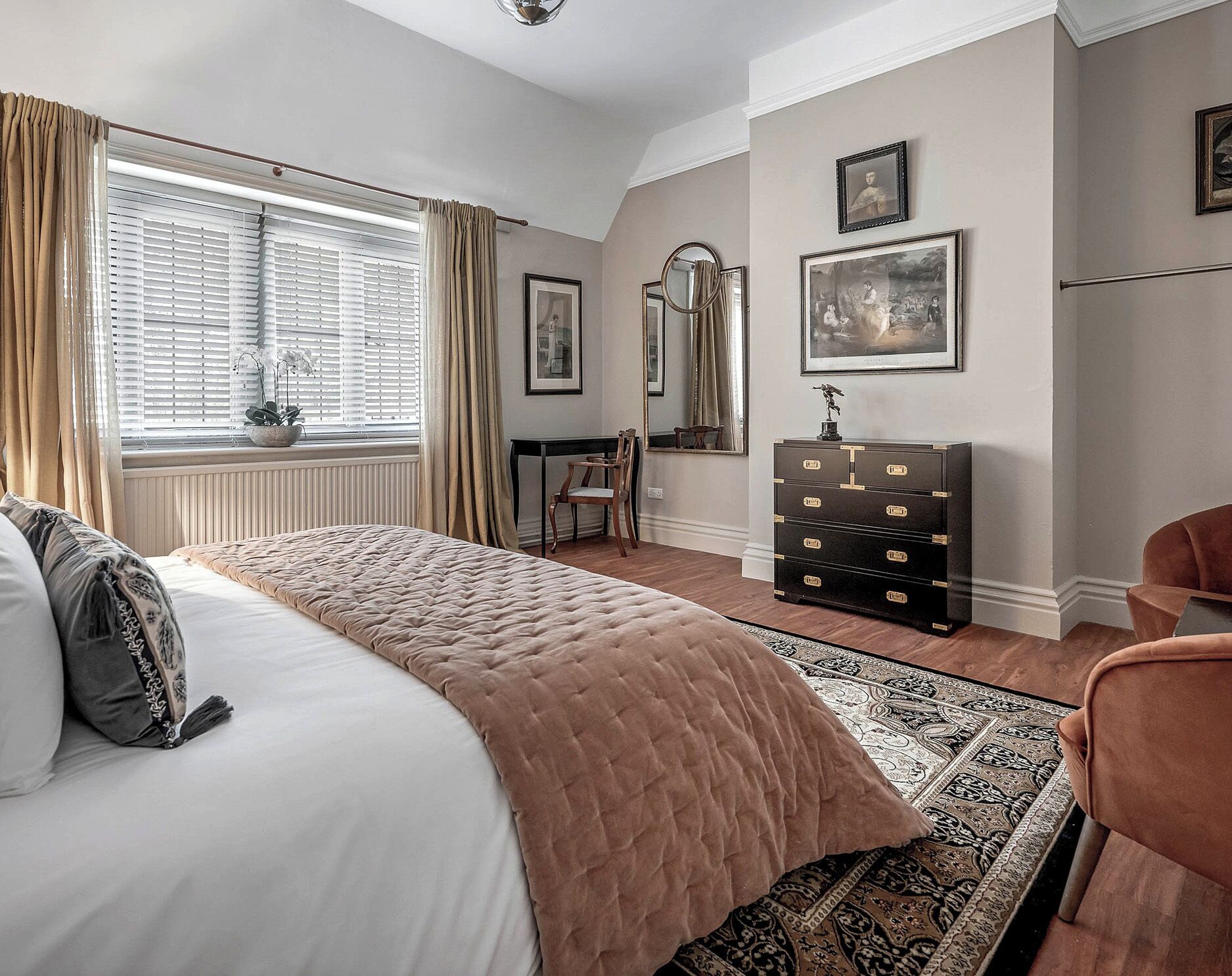 A bedroom with a large bed, a dresser, a chair, and a window with curtains.