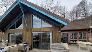 A wooden building with a large deck, sliding glass doors, and outdoor furniture.
