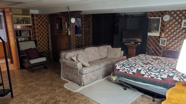 A room with a sofa, a bed, a small table, and a chair.