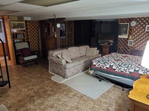 A room with a sofa, a bed, a small table, and a chair.