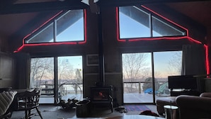 A cozy interior with a fireplace, a dining table, and large windows with red LED lighting.