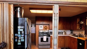 A compact kitchen with wooden cabinets, a refrigerator, an oven, and a microwave.