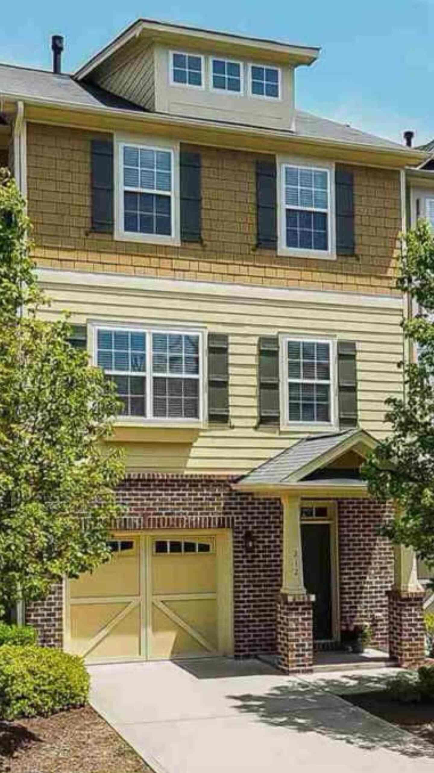 A two-story residential building with a garage and a brick facade.