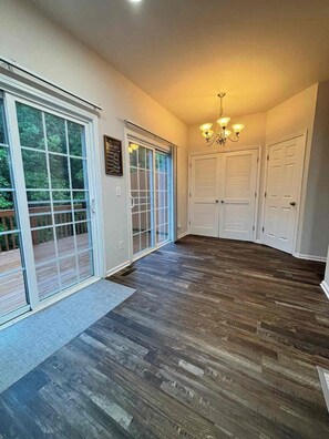 A hallway with a wooden floor, a sliding glass door, and a chandelier. - Spacious 4-bedroom townhome Cary/Morrisville area (Cary)